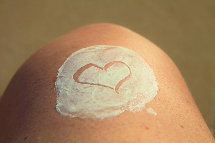 image of a person's knee with white sunscreen and a hearth drawn into the sunscreen